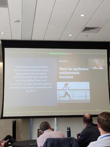 Attendees at the NAIFA Utah Symposium watch a presentation discussing retirement income confidence and guaranteed lifetime income strategies during a financial planning session.