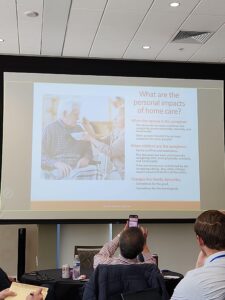 Presentation slide at the NAIFA Utah Symposium discussing the personal impacts of home care and caregiving on spouses, children, and family dynamics, viewed from the audience during a retirement and long-term care planning session.